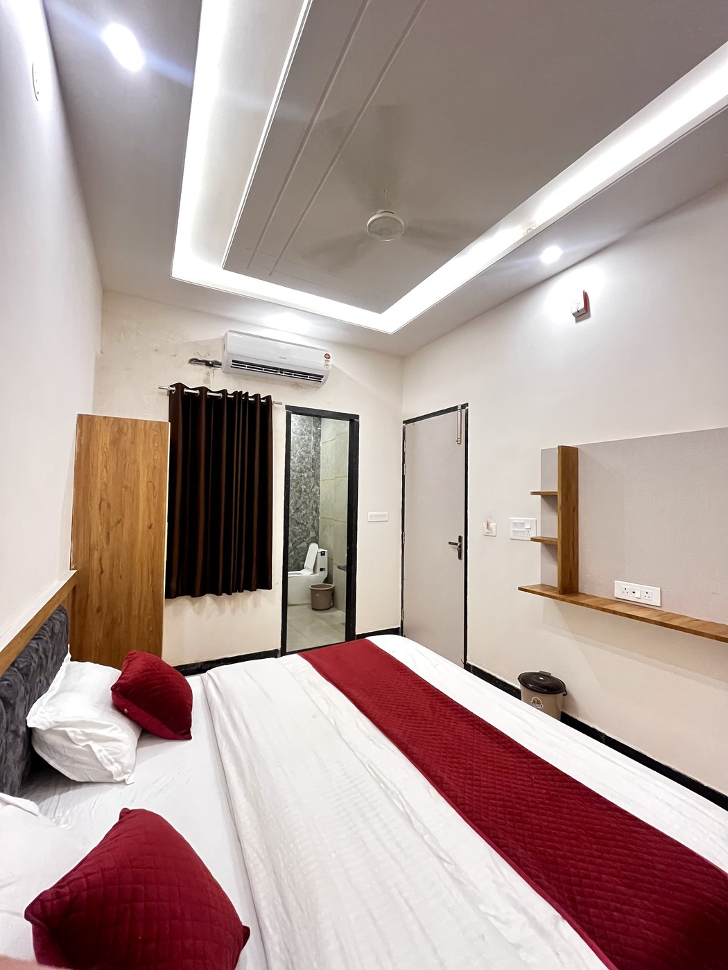 Comfortable king bed with plush pillows, red runner, split AC and modern attached bathroom