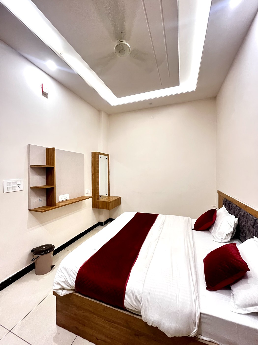 Spacious king bedding view with built-in wooden dressing vanity, mirror and tray ceiling lighting